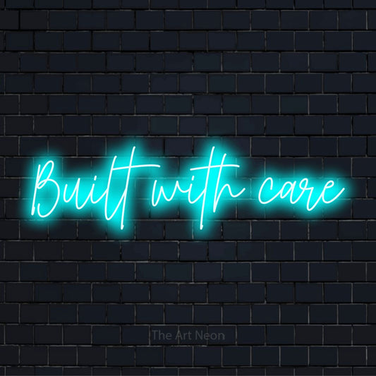 "Built With Care" script-style LED neon sign on a black brick wall