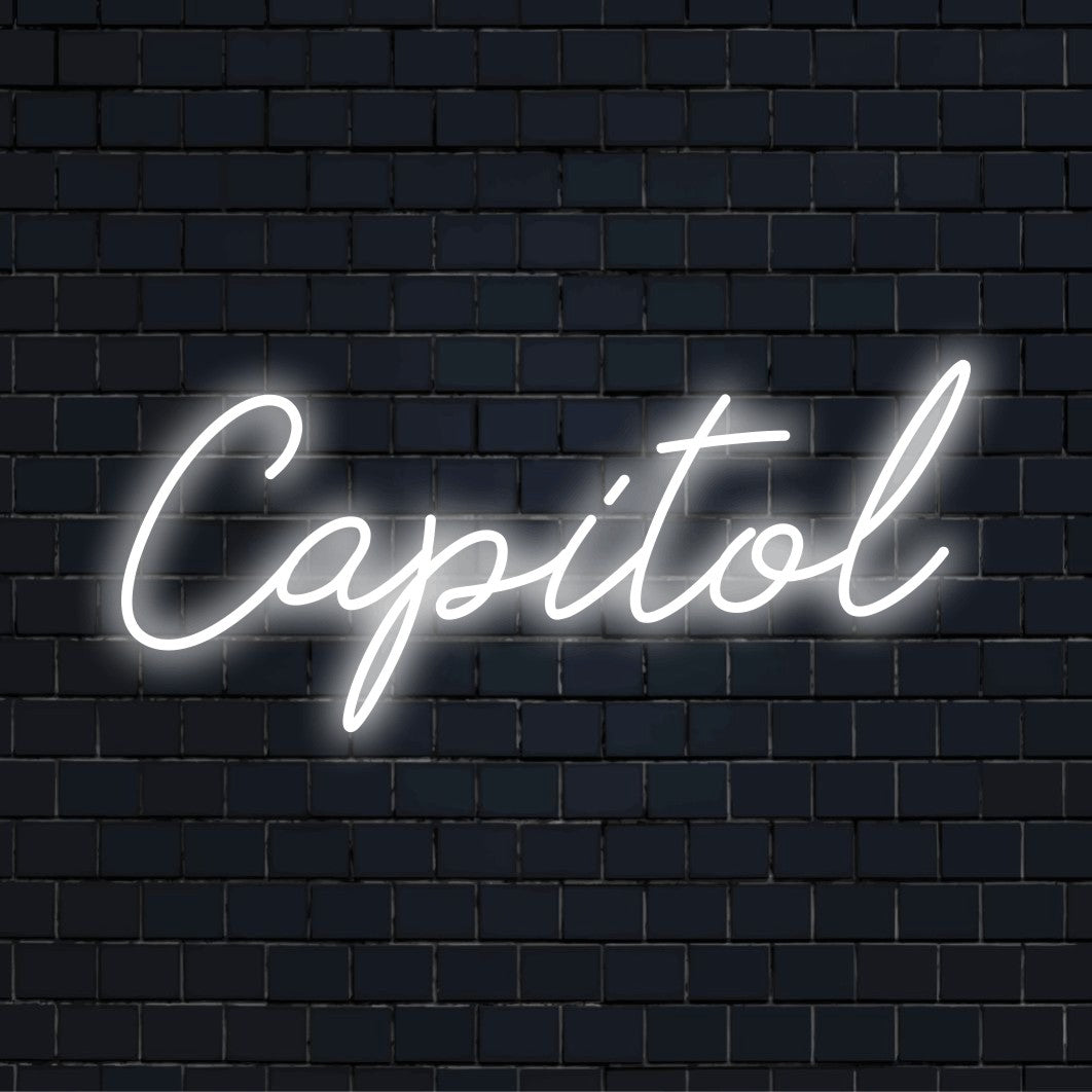 Capitol Neon Light with bright neon lettering against black brick wall