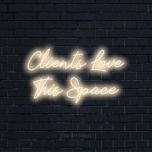 "Clients Love This Space" LED neon sign on a black brick wall