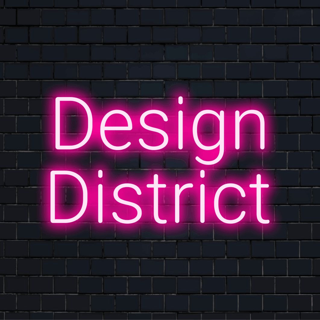 Design District LED Neon Sign, bright neon lettering on dark brick background