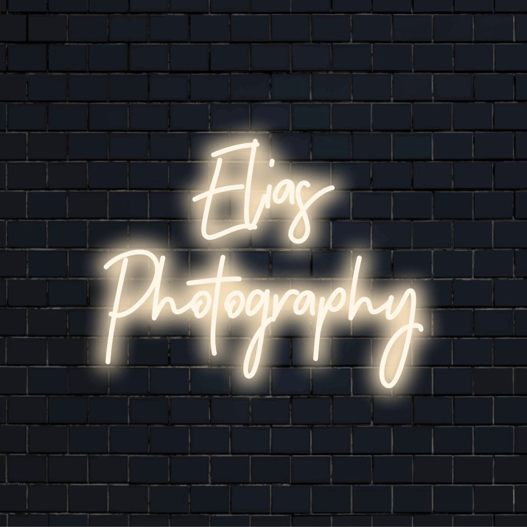 Elias Photography Custom Name Neon Sign, bright neon lettering against black brick wall
