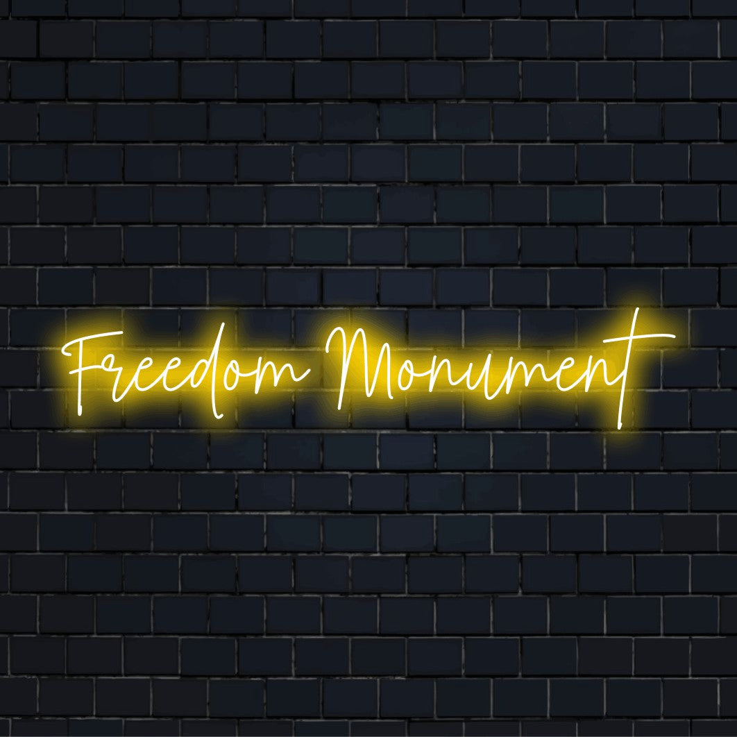 Freedom Monument Neon Light with glowing neon text against brick backdrop