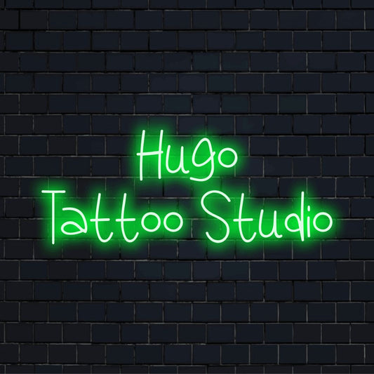 Hugo Tattoo Studio Custom Name Neon Sign, bright neon glow against brick backdrop