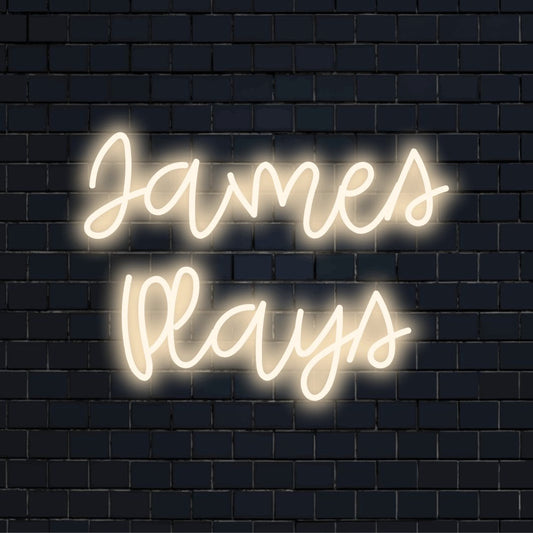 James Plays Custom Name Neon Sign, bright neon lettering on dark brick background