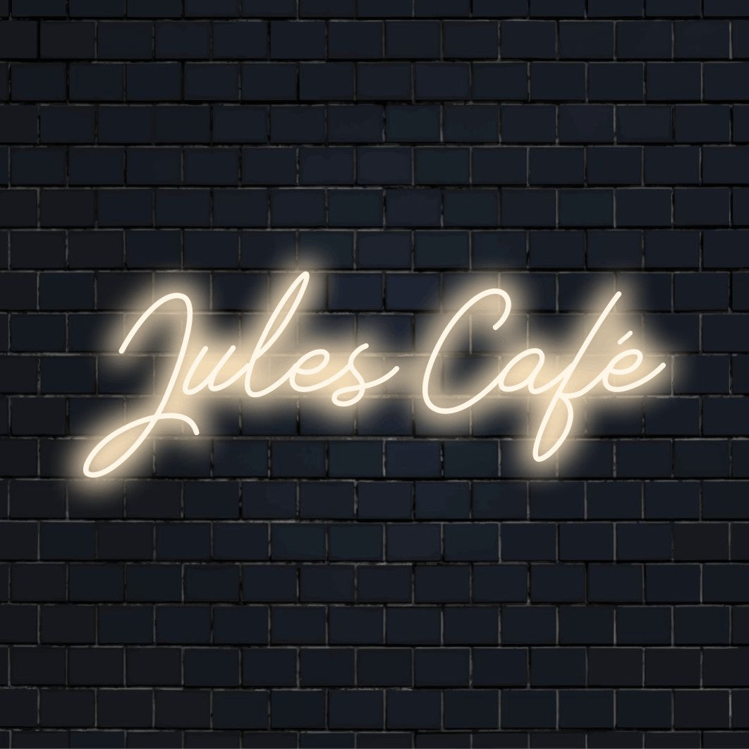 Jules Cafe Custom Name Neon Sign, bright neon glow against black brick wall
