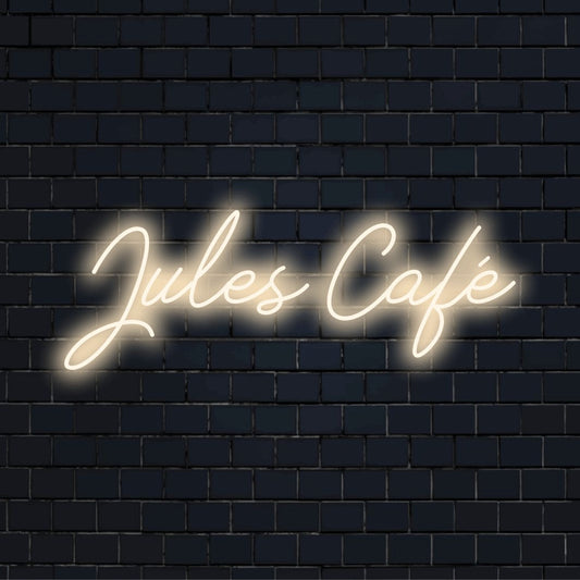 Jules Cafe Custom Name Neon Sign, bright neon glow against black brick wall