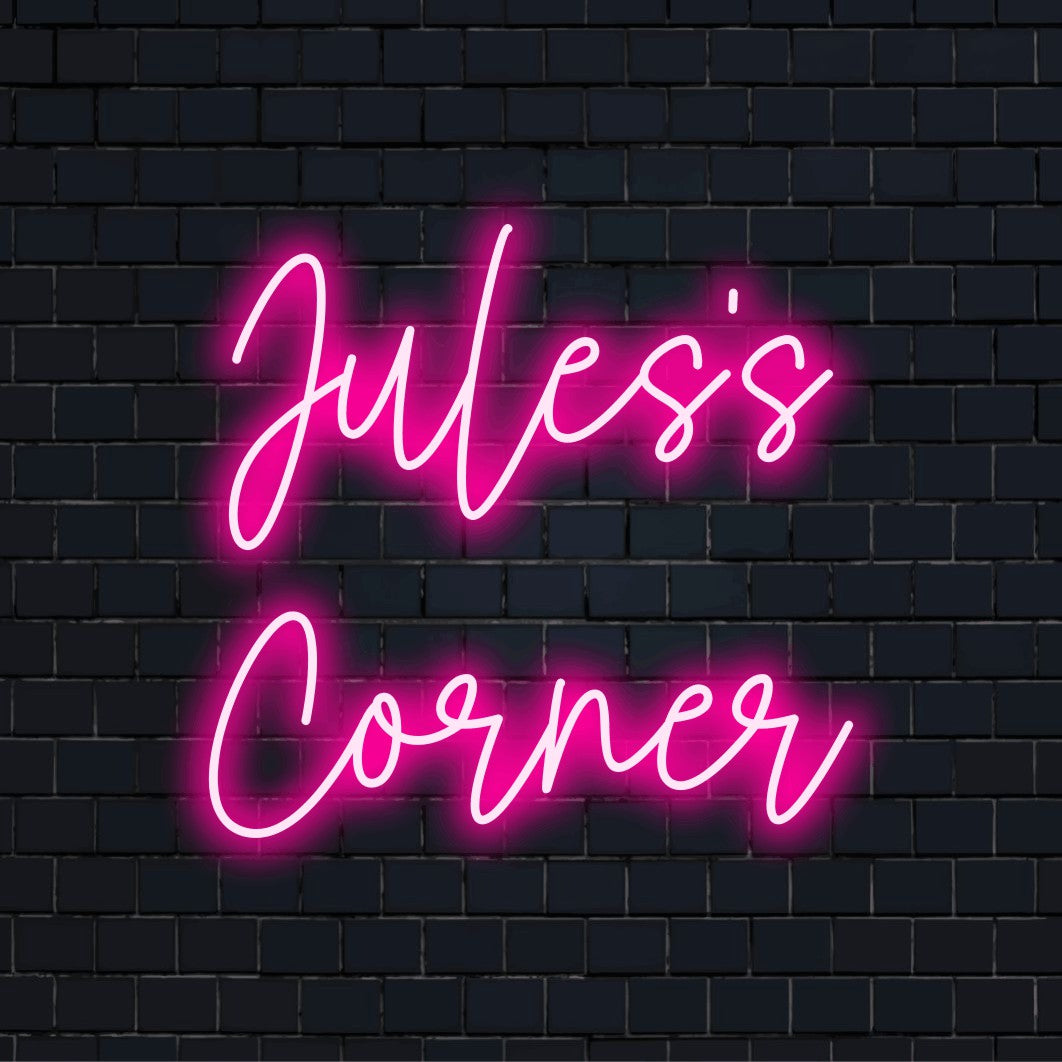 Jules_s Corner Custom Name Neon Sign, soft neon glow against black brick wall