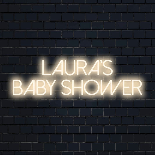 Laura_s Baby Shower Personalized LED Neon Sign, glowing lettering against black brick wall