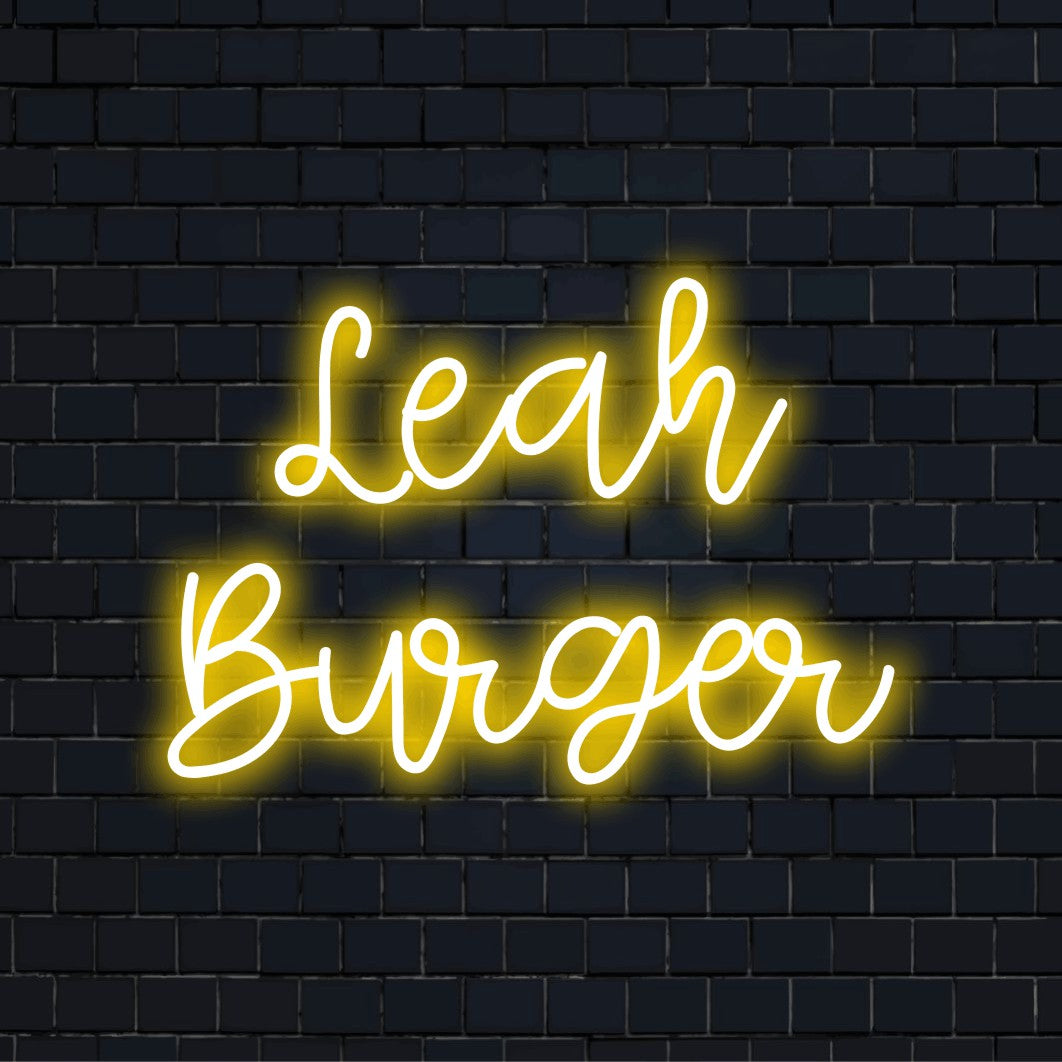 Leah Burger Custom Name Neon Sign, glowing lettering against black brick wall