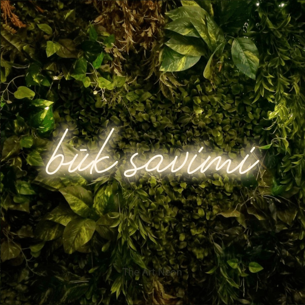 LED neon sign reading “būk savimi”, arranged in a single line.