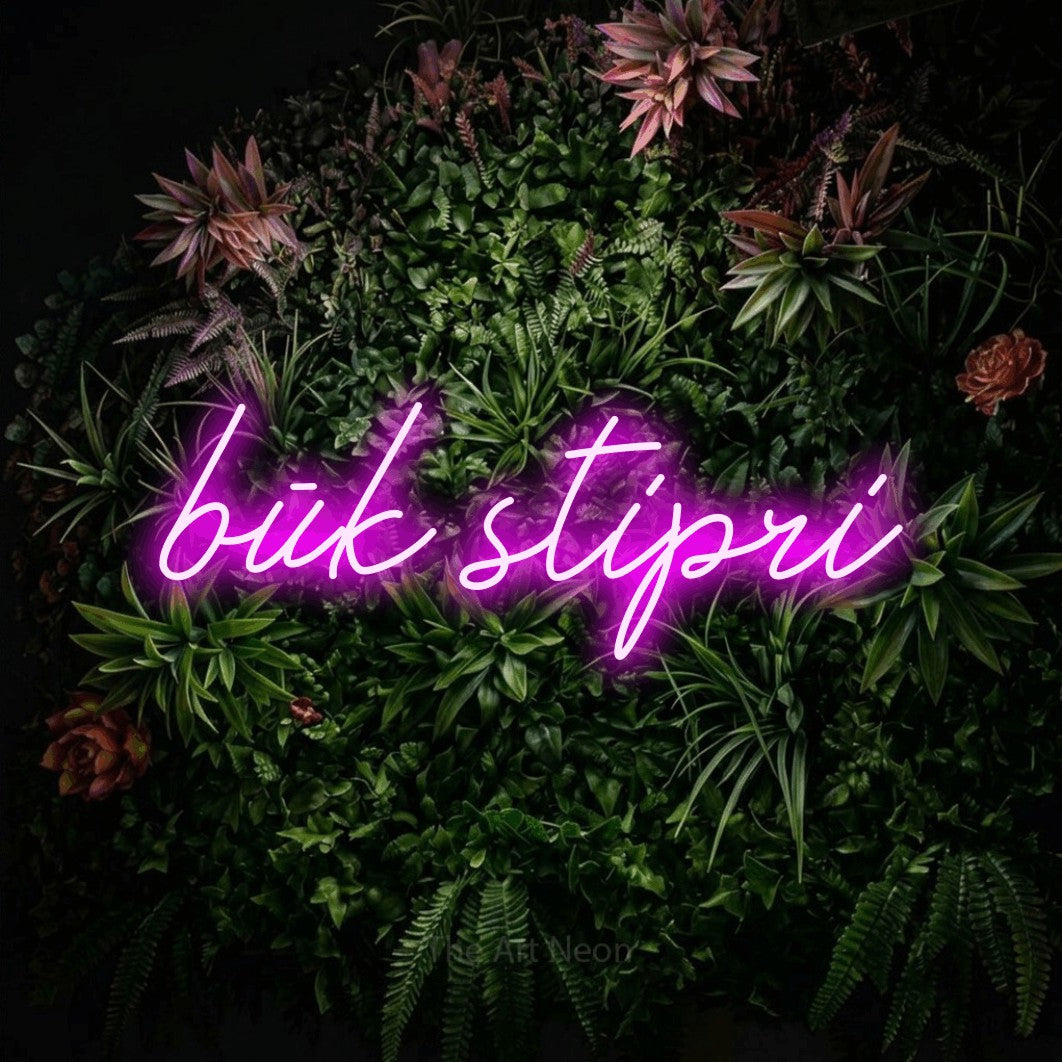 LED neon sign reading “būk stipri”, arranged in a single line.