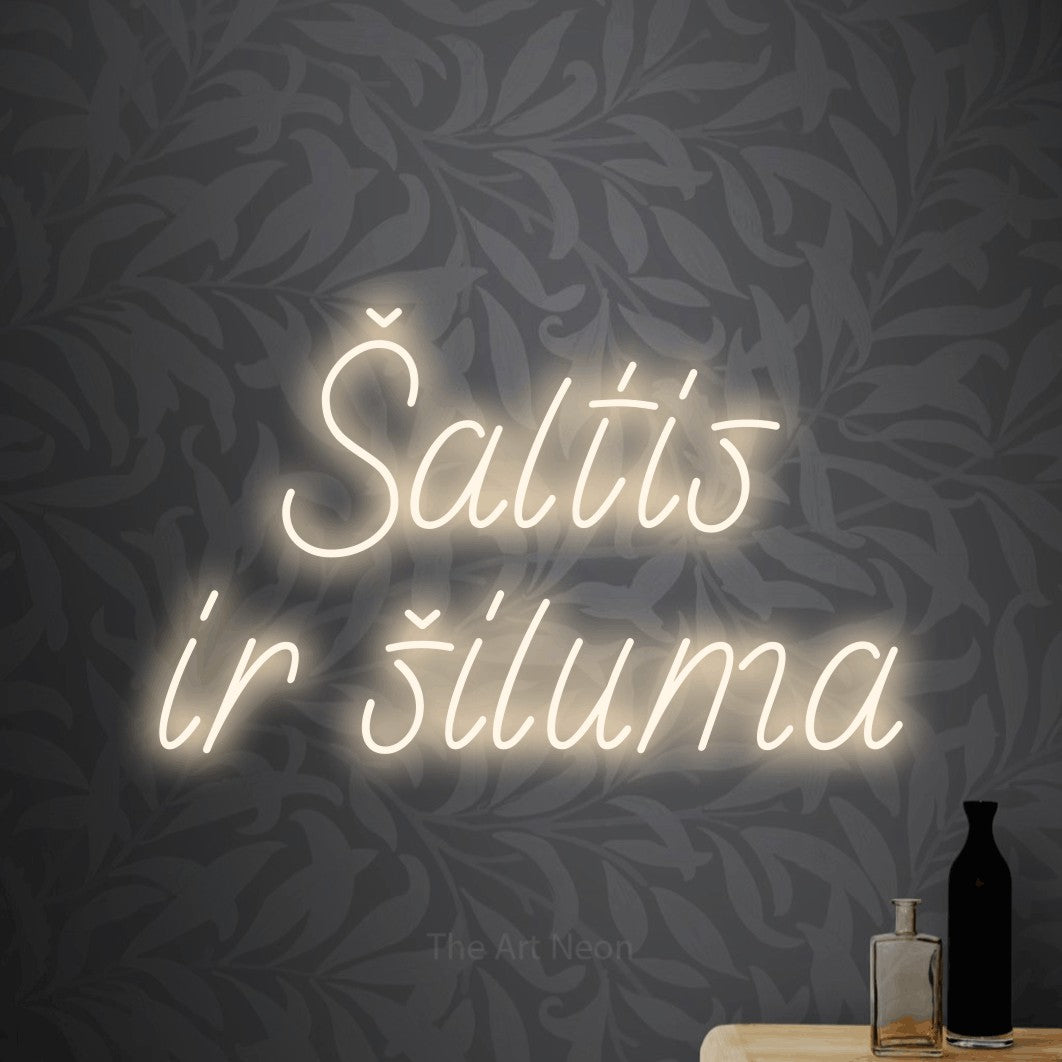 LED neon sign reading “Šaltis ir šiluma”, arranged in two lines.