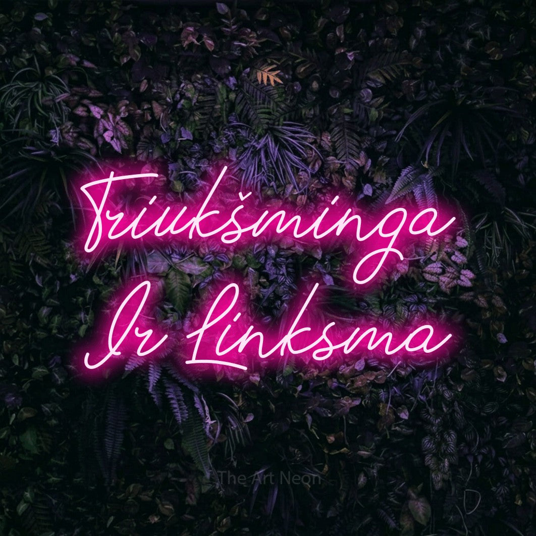 LED neon sign reading “Triukšminga Ir Linksma”, arranged in two lines.