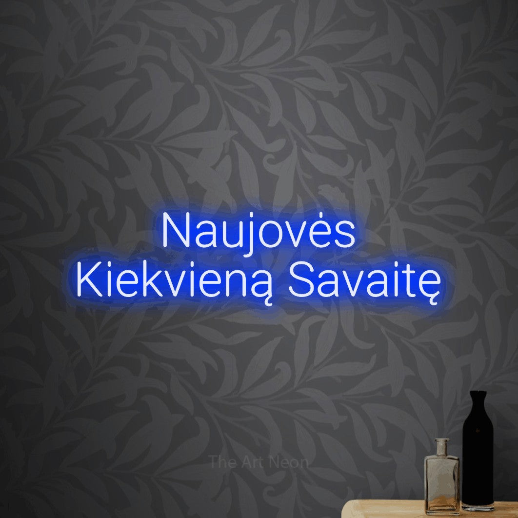 LED neon sign reading “Naujovės Kiekvieną Savaitę”, arranged in two lines.