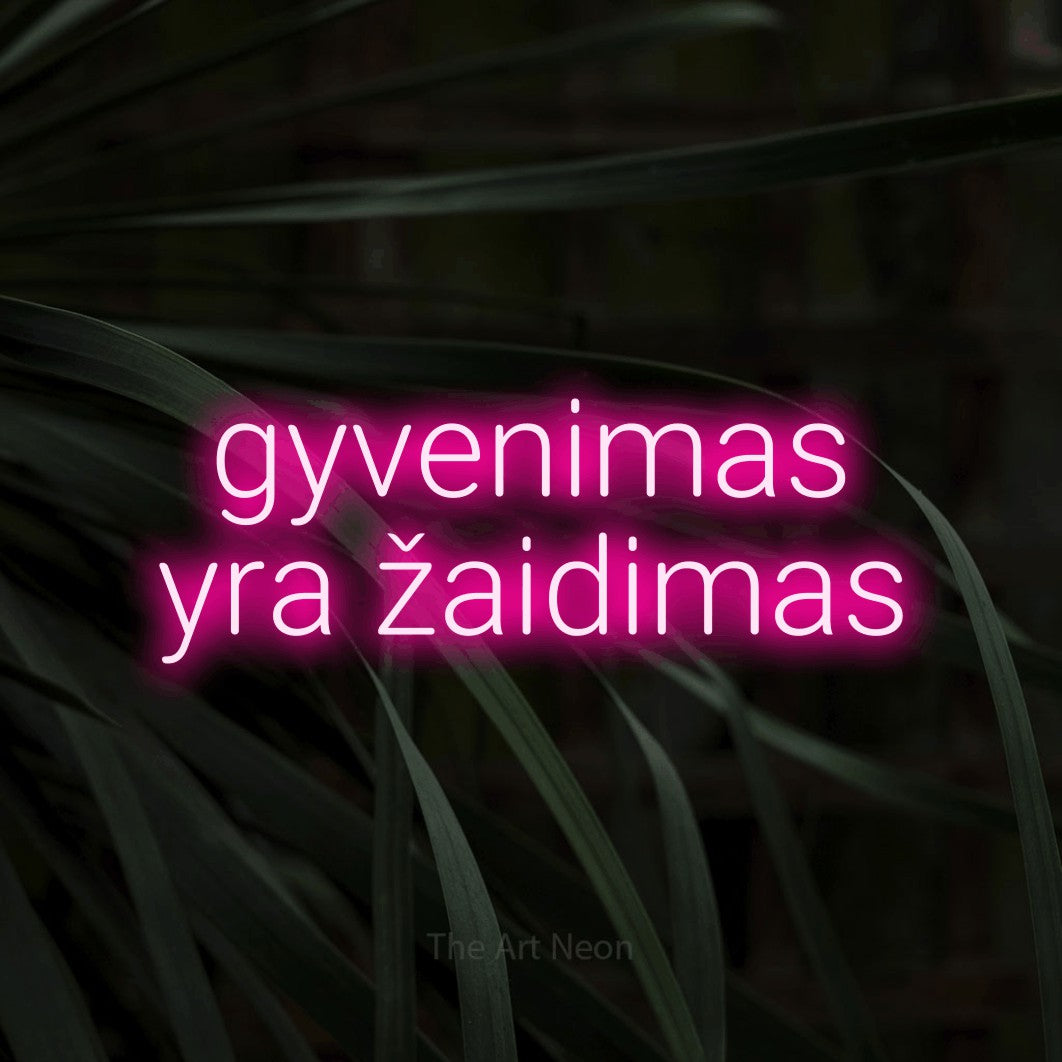 LED neon sign reading “gyvenimas yra žaidimas”, arranged in two lines.