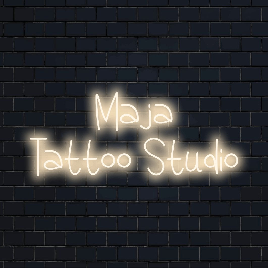 Maja Tattoo Studio Personalized LED Neon Sign, bright neon glow on dark brick wall