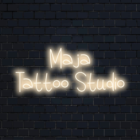 Maja Tattoo Studio Personalized LED Neon Sign, bright neon glow on dark brick wall