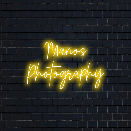 Manos Photography Custom Name Neon Sign, glowing lettering against brick backdrop
