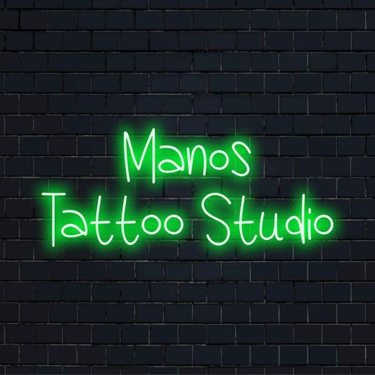 Manos Tattoo Studio Custom Name Neon Sign, neon text light against black brick wall