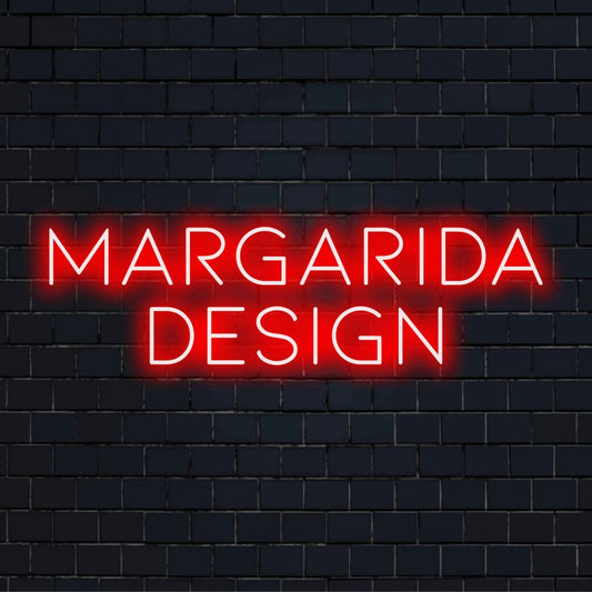 Margarida Design Custom Name Neon Sign, glowing lettering against black brick wall