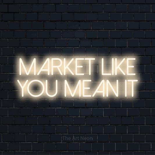 "Market Like You Mean It" script-style LED neon sign on a black brick wall