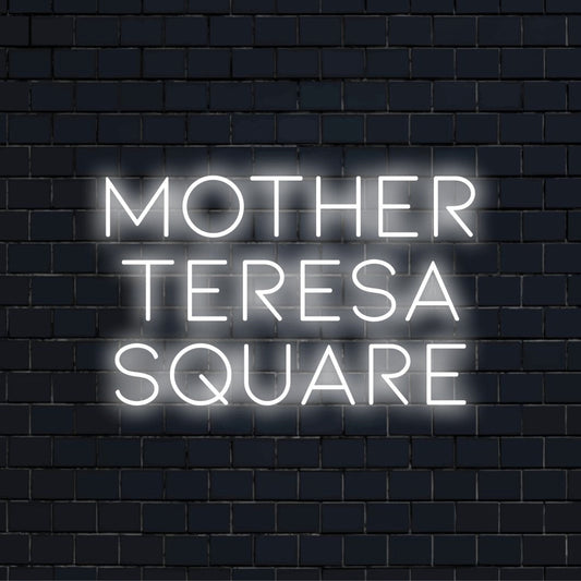 Mother Teresa Square Neon Sign, glowing lettering against brick backdrop
