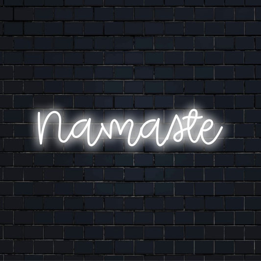 Namaste LED Neon Sign, bright neon lettering against black brick wall