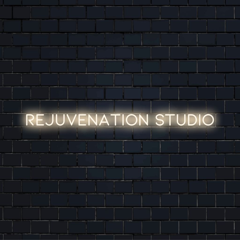 Rejuvenation Studio Neon Sign, glowing lettering on dark brick wall