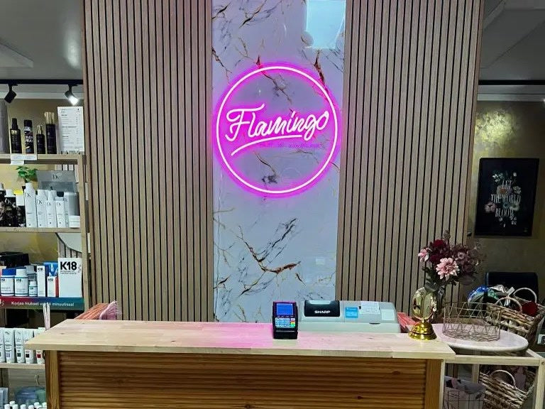 Růžové neonové logo Flamingo instalované za recepčním pultem v Parturi-Kampaamo Flamingo