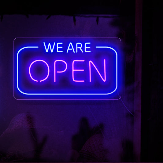 A captivating neon sign proudly displaying the words 'We are Open' in bold, glowing letters, signaling that a business is ready and available to serve its customers. 