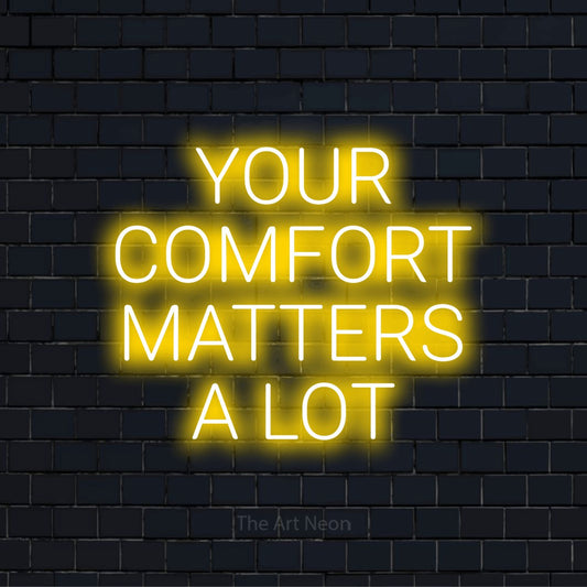 "Your Comfort Matters A Lot" glowing LED neon sign on a black brick wall