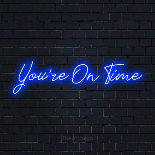 "You’re On Time" neon text design on a black brick wall